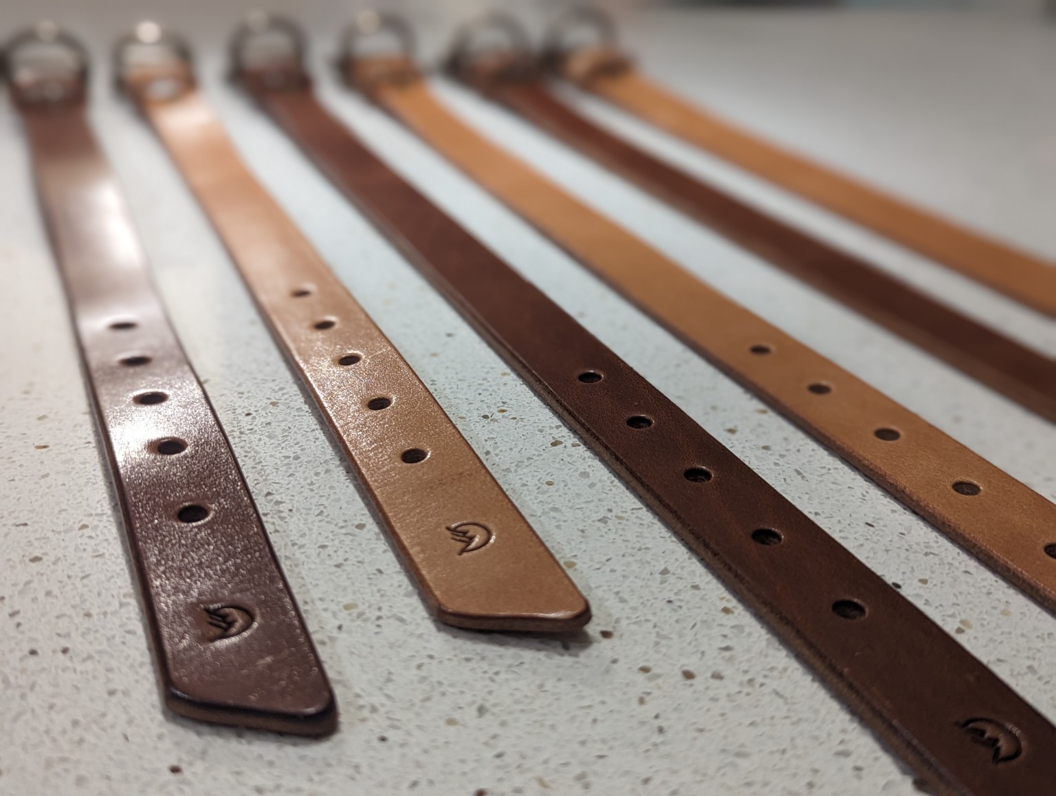 Multiple Moonlight Leatherworks belts shown in a lineup of leather colors