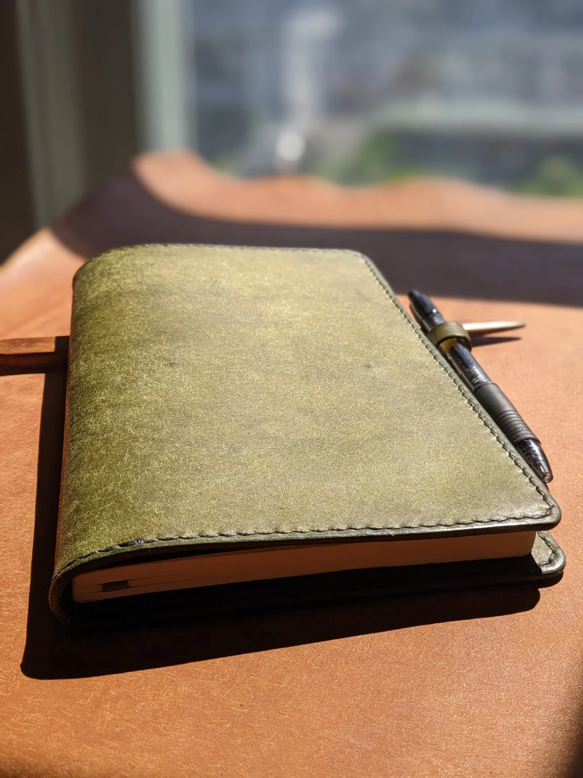 Olive leather Moonlight Leatherworks journal cover photographed on the workbench