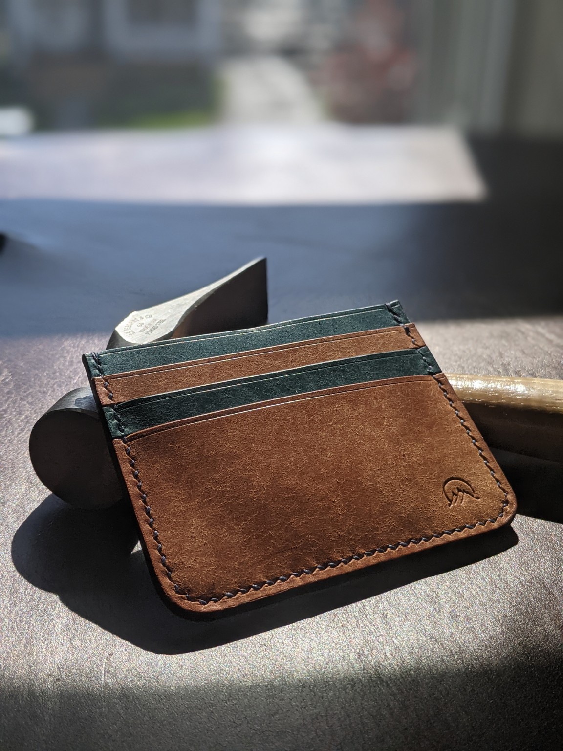A Moonlight Leatherworks signature wallet photographed on a workbench in window light