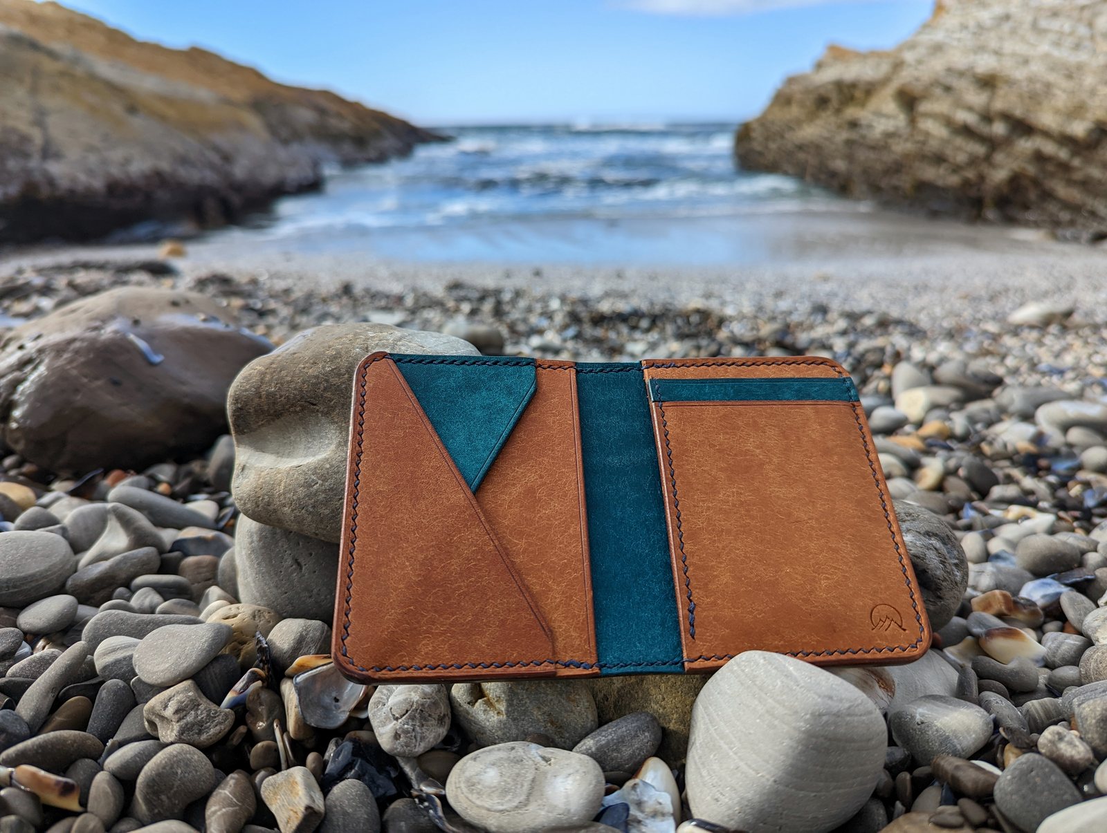 Moonlight Leatherworks signature wallet photographed on coastal stones