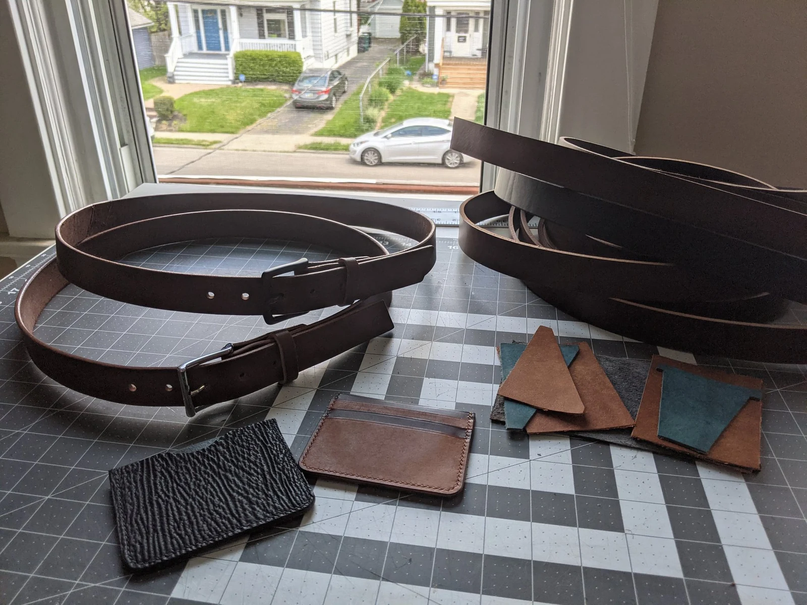 Moonlight Leatherworks workbench with finished belts, wallets, and leather pieces in progress