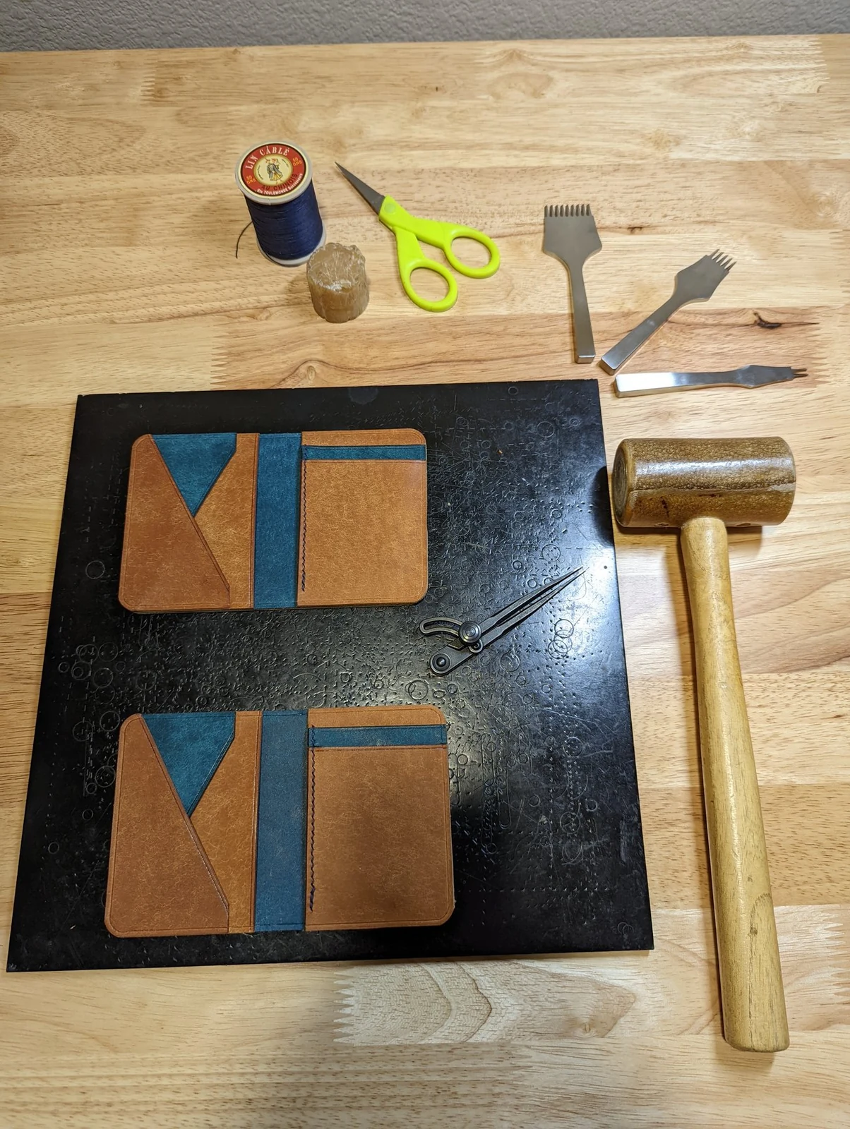 Two wallet panels further along in the hand-building process beside leatherworking tools